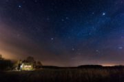 Verlicht tiny house onder een sterrenhemel