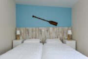 Slaapkamer met blauwe wand en peddel boven het bed