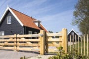 Zwart vakantiehuis met houten hek, in Zeeland