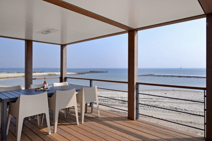 Overdekt terras aan het strand met eettafel met 6 stoelen