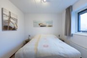 Slaapkamer met tweepersoons bed en schilderijen aan de wand