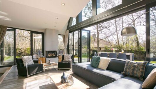 Grote woonkamer met zonlicht en een grote open schuifpui