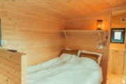 Tweepersoonsbed in een houten tiny house
