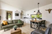 Woonkamer met groene zitbank, 4-persoons eethoek en witte keuken