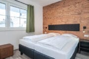 Slaapkamer met houten achterwand en twee aan elkaar geschoven boxspring bedden