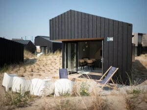 Strak vakantiehuis met zwart hout en witte tuinstoelen